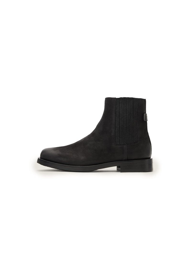 Stivali Chelsea in suede neri con pannelli elastici a coste sui lati e un asola, caratterizzati da una punta arrotondata e un tacco a blocco basso.