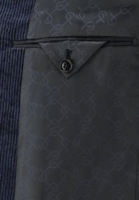 Herrenjacke mit einer strukturierten, dunkelblauen Cordura-Stoffseite und einer glatten, gemusterten schwarzen Stoffseite; inklusive einer geknöpften Tasche.