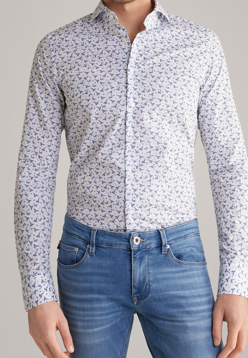 Wit overhemd met lange mouwen en knopen, bedrukt met een patroon van blauwe vogels. Slim fit met een klassieke kraag, gecombineerd met lichtblauwe spijkerbroek.