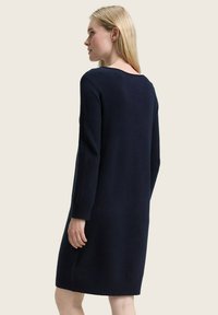 Marineblaues Strickkleid aus weichem Strickstoff. Es hat lange Ärmel, eine lockere Passform und gerippte Akzente an den Bündchen und dem Saum.