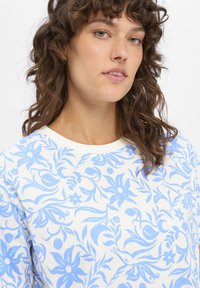 Witte katoenen sweatshirt met een blauw bloemmotief met krullen en details, ronde halslijn en zachte textuur.