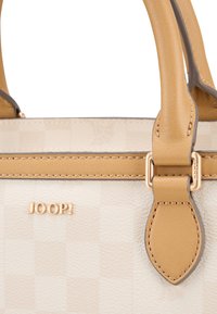 Sac à main couleur crème avec un motif en damier, des accents en cuir tan et des accessoires en or. Présente un logo et des détails cousus sur les poignées.
