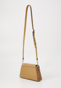 Borsa in pelle e suede marrone con forma trapezoidale, hardware in argento e tracolla regolabile. Presenta una texture liscia e dettagli di cucitura.