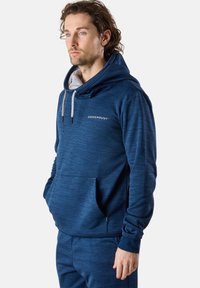 Felpa blu, con texture, dotata di un alto colletto, cordini e una tasca frontale. Presenta una fodera interna grigia a contrasto e un logo ricamato.