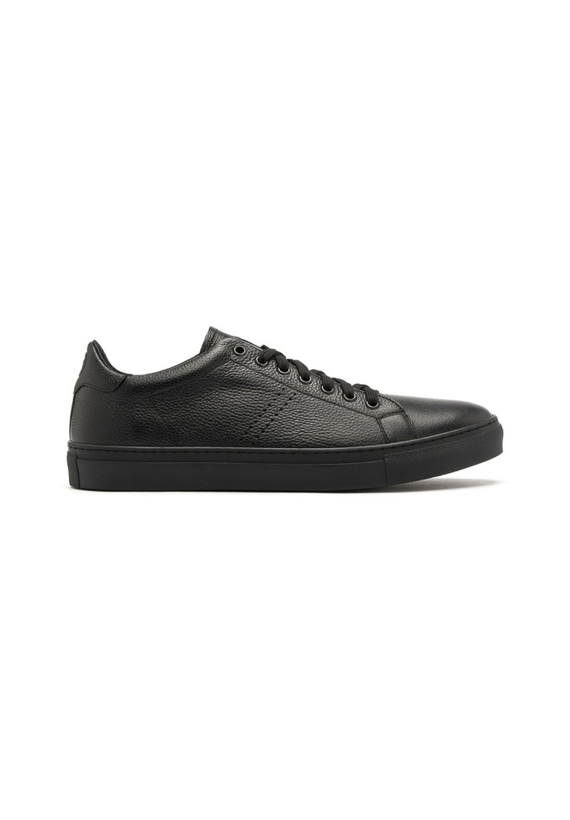 Baskets en cuir noir avec une surface texturée, bout rond, semelle plate en caoutchouc noir, et six œillets pour les lacets, présentant un design minimaliste.