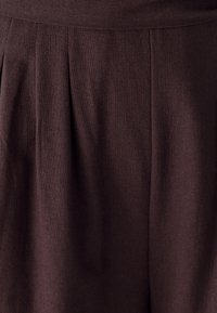 Tela marrón texturizada con pliegues visibles y una cinturilla suave, que presenta una forma estructurada y un color uniforme en toda su extensión.