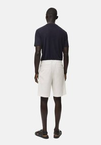 Marineblaues Kurzarm-T-Shirt, kombiniert mit hellgrauen gestreiften Shorts und schwarzen Sandalen. Das Outfit ist lässig und hat eine lockere Passform.