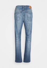 Jasnoniebieskie dżinsy z denimu o prostych nogawkach, wyposażone w dwie tylne kieszenie oraz brązową skórzaną metkę na pasku. Gładka faktura.