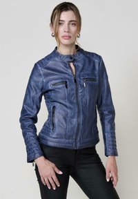 Giacca di pelle blu con zipper frontale, colletto alto e diverse tasche con zip. Presenta pannelli testurizzati sulle spalle e sulle maniche.