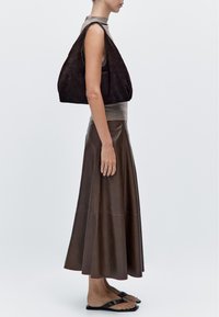 Suede brown handbag, sleeveless top in light gray, and a brown leather skirt with a flared hem, paired with flat black sandals.