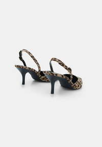 Pair of open-back slingback heels with leopard print straps and black pointed stiletto heels on a white background.