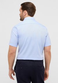 Lichtblauwe short-sleeve shirt gemaakt van een gladde stof, met een klassieke kraag en een rechte snit. De achterkant toont de naaddetails en de mouwen.