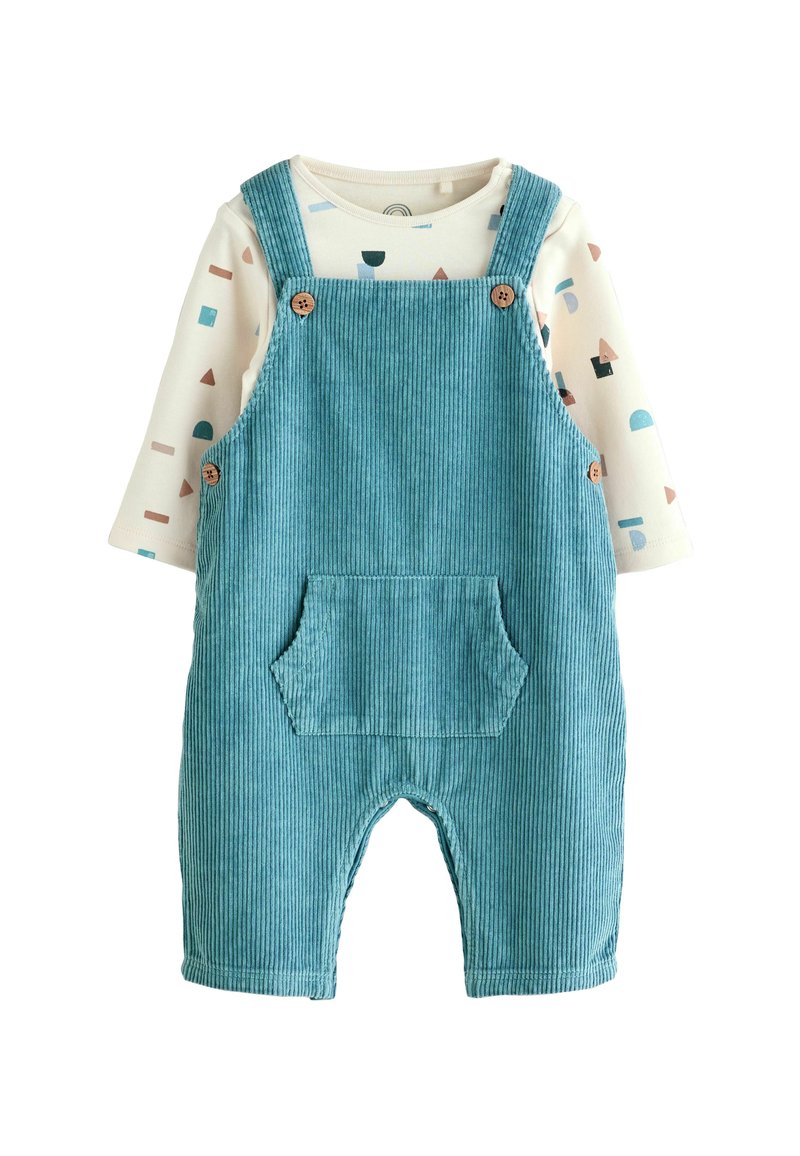 Türkise Corduroy-Baby-Latzhose mit Fronttasche, über einem cremefarbenen Langarmshirt mit mehrfarbigen geometrischen Formen.