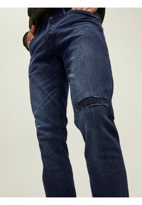 Jeans in denim blu scuro con dettaglio strappato al ginocchio. Caratterizzati da un classico design a cinque tasche e una vestibilità slim dritta.