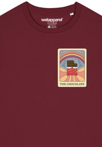 Bordeauxrotes Baumwoll-T-Shirt mit einem rechteckigen Grafikdesign, das einen Schokoladenriegel, einen Regenbogen und eine bergige Landschaft zeigt, beschriftet mit "DIE SCHOKOLADE."