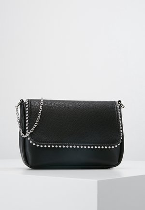Zwarte leren schoudertas met gestructureerde klep, zilverkleurige studs en zilveren kettingriem, geplaatst op een wit voetstuk tegen een effen achtergrond.