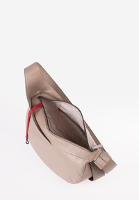 Borsa a tracolla in pelle beige con una tasca con zip, foderatura interna a motivo e tracolla con accento rosso. Texture liscia, forma curvata.