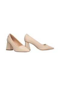 Zapatos de cuero beige con tacón cuadrado, punta afilada y textura suave. Presentan una ligera curva en la parte trasera y una suela rígida.