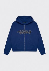 Granatowa bluza z kapturem zapinana na zamek, wykonana z miękkiego materiału, z kieszenią kangurką, ściągaczami przy mankietach oraz napisem "TROUBLE" w białym skrypcie na klatce piersiowej.