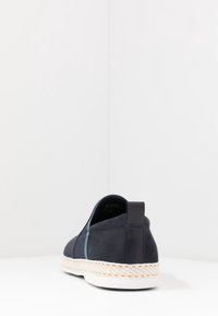 Scarpe slip-on in camoscio blu navy con una striscia azzurro chiaro, suola in juta stile espadrilles e un tallone nero per maggiore supporto.