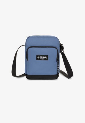 Kleine blaue Eastpak Umhängetasche mit schwarzem Boden, vorderer Reißverschlusstasche und verstellbarem schwarzem Schultergurt vor weißem Hintergrund.