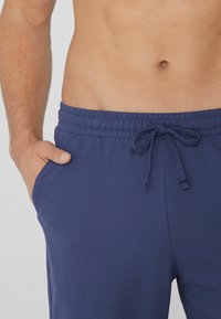 Námořnické modré kraťasy vyrobené z texturované látky s elastickým pasem a nastavitelnou šňůrkou, s bočními kapsami.