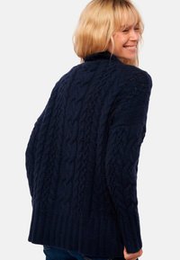 Pull en maille torsadée bleu marine avec col montant, ourlet côtelé et motifs texturés. Conçu avec une coupe décontractée et des manches longues.