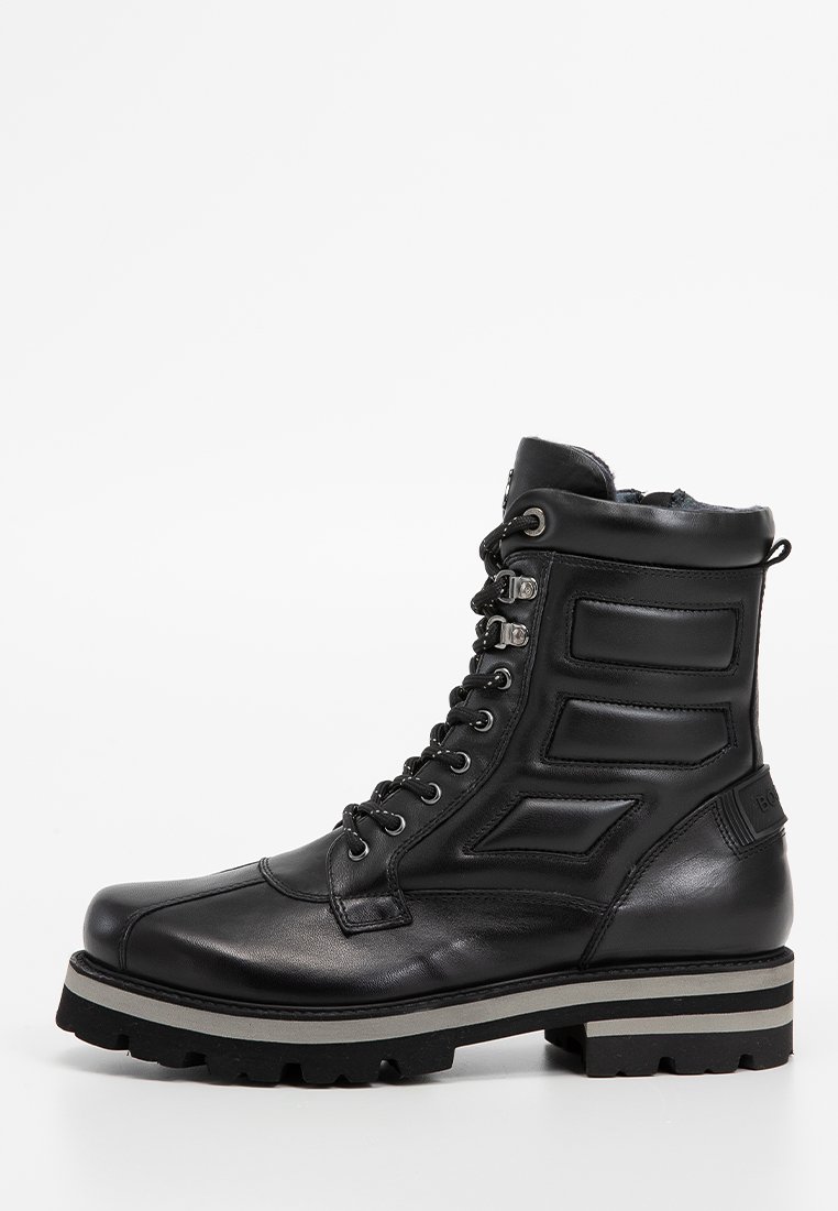 Schwarzer Leder-Komfortstiefel mit gepolsterter Knöchelpartie, strukturierten Einsätzen, silbernen Beschlägen und einer dicken Sohle mit einem weißen Streifen.