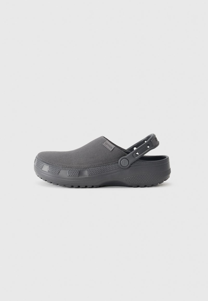 Sabot gris foncé à enfiler avec empeigne en tissu, bride de talon ajustable et semelle texturée, montré de profil sur fond neutre.