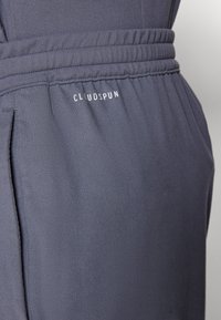 Mørkegrå joggerbukser har en elastisk talje med samlet detaljering og et hvidt "CLOUDSPUN" logo fortil.
