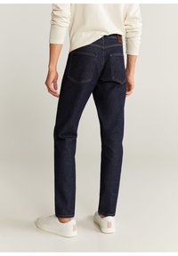 Jeans in denim blu navy con una vestibilità a gamba dritta, caratterizzati da due tasche posteriori, cuciture visibili e un'etichetta in pelle marrone sulla vita.