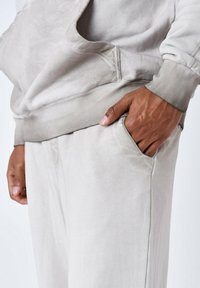 Lichtgrijs, zacht sweatshirt met een kangoeroezak en geribbelde manchetten, gecombineerd met bijpassende losvallende broek met zijzakken.