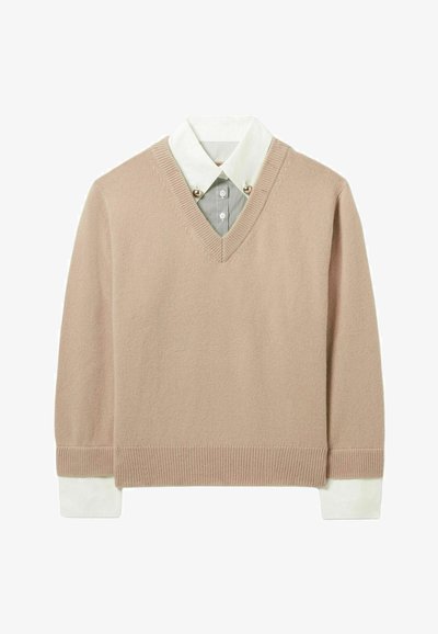 Pull en V en tricot beige doux avec un ourlet et des poignets côtelés, comportant une chemise col blanc en dessous avec de fines rayures et des boutons décoratifs.