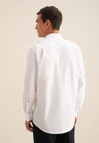 Witte overhemd met lange mouwen van gladde stof, met een klassieke kraag en een afgeronde zoom, voorzien van knoopmanchetten en subtiele decoratieve accenten.