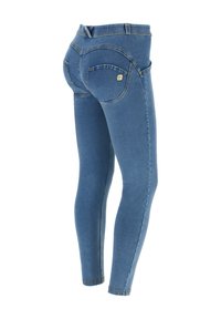 Jean skinny bleu avec poches arrière, passants de ceinture, et un petit logo carré sur la poche droite, vu d'un angle arrière.