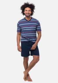 Miestenské tričko s krátkym rukávom v námornícke modrej farbe s pruhmi v šedej a červenej farbe, v kombinácii s námorníckymi šortkami. Ľahký materiál, voľný strih, bez viditeľných log. 