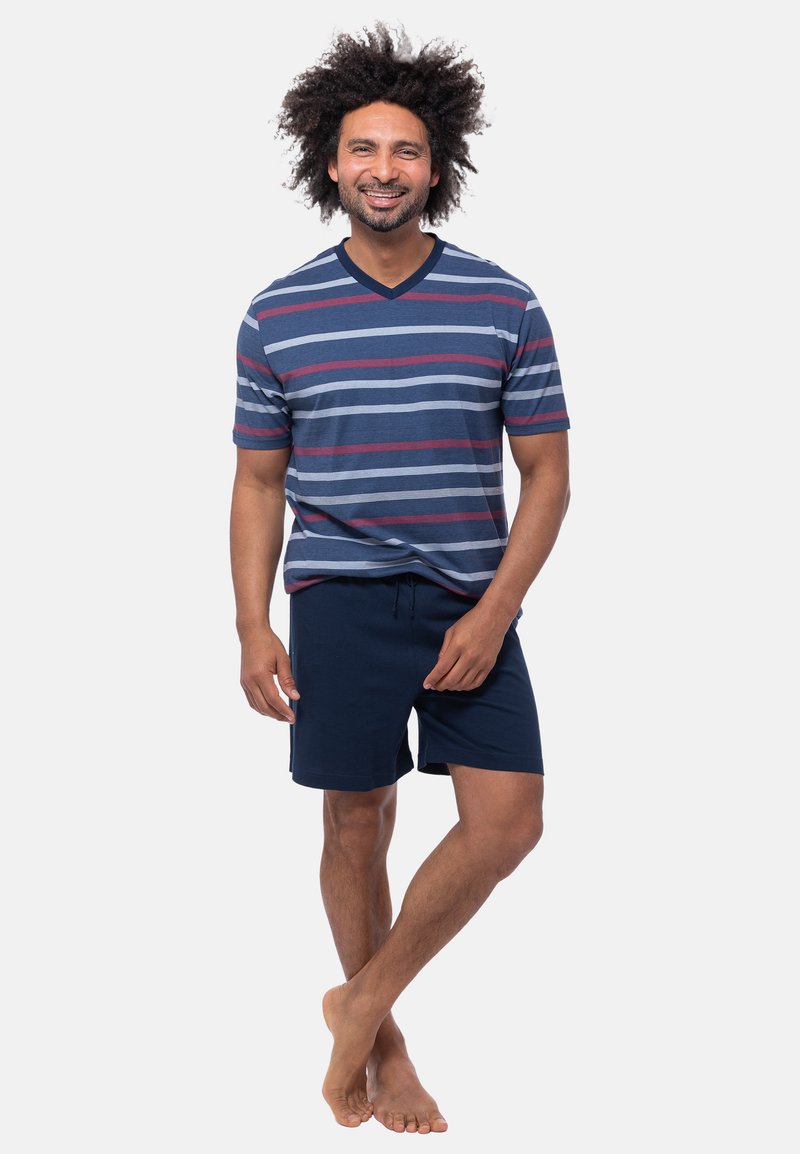 Miestenské tričko s krátkym rukávom v námornícke modrej farbe s pruhmi v šedej a červenej farbe, v kombinácii s námorníckymi šortkami. Ľahký materiál, voľný strih, bez viditeľných log.