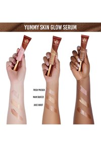 Tubos de serum Yummy Skin Glow en rosa y bronce, mostrando tres tonos: Fresh Pressed, Main Squeeze y Juice Boost en los brazos.