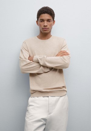 Beige lightweight sweater with long sleeves and a round neckline, paired with light-colored trousers. Minimalistic design and smooth texture.