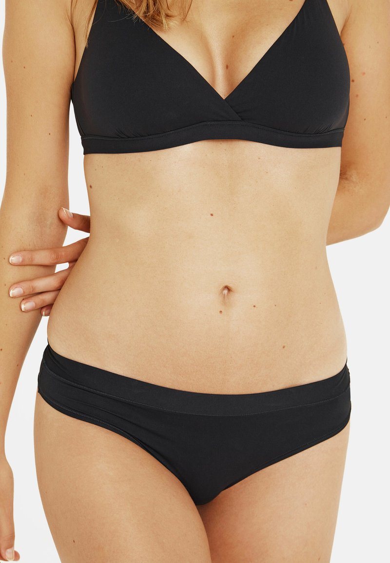 Ensemble de bikini noir comprenant un haut bralette en triangle et un bas hipster taille basse. Tissu lisse avec des coutures minimales et sans matériel visible.