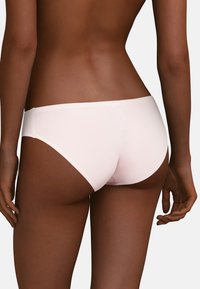 Lyserødt sømløst undertøj med lavtaljet design, glat tekstur og minimalistisk stil, med en enkel linning og uden synlige sømme.