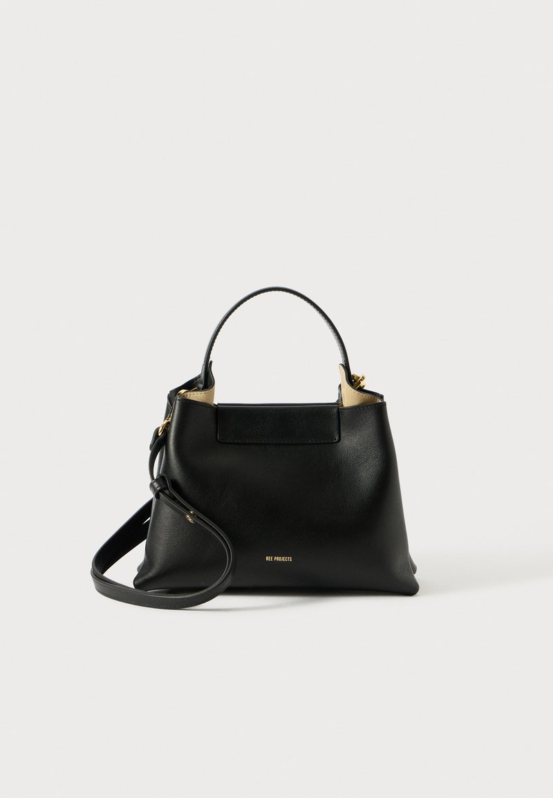 Sac à main en cuir noir avec une silhouette structurée, accents en matériel doré, poigne courte et bandoulière amovible. Design bicolore.