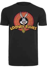 Melnā kokvilnas T-kreklā ir centrāla Bugs Bunny grafika, dzeltenais "LOONEY TUNES" teksts un koncentriska sarkana un melna apļa dizains.