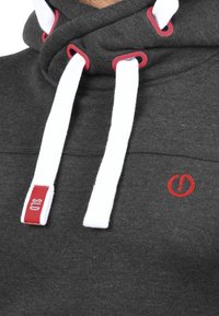 Dark gray hoodie with a high neckline, white drawstrings, red eyelets, and a small red logo on the front. Soft fabric texture.