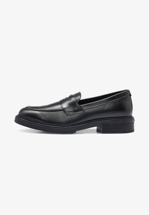 Mocassin noir en cuir à enfiler avec un petit talon empilé et un détail de lanière à sou sou sur le dessus, présenté de profil sur un fond blanc.
