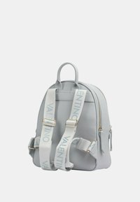 Zaino in pelle grigia con forma arrotondata, accessori in oro e spallacci larghi che presentano il logo "Valentino" in azzurro chiaro.