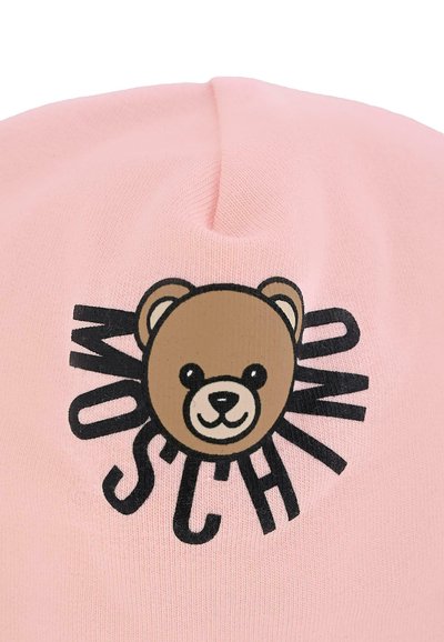 Różowa, dziergana czapka z grafikom przedstawiającym brązowego misia i czarnym tekstem wokół niego, tworząca zabawny wzór. Miękka tekstura i dopasowane wykończenie.