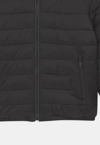 Sort dunjakke med quiltet design, lynlås foran og en lynlåslomme i siden. Materialet virker glat og let.