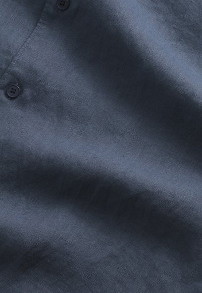 Navy blue button-up shirt made of textured linen. Features a v-neck collar and two dark buttons at the neck, showcasing a smooth fabric surface.