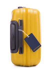 Žlutý tvrdý kufr s texturovaným povrchem, černou rukojetí a zipem, a modrou visačkou označenou "WITTCHEN."
